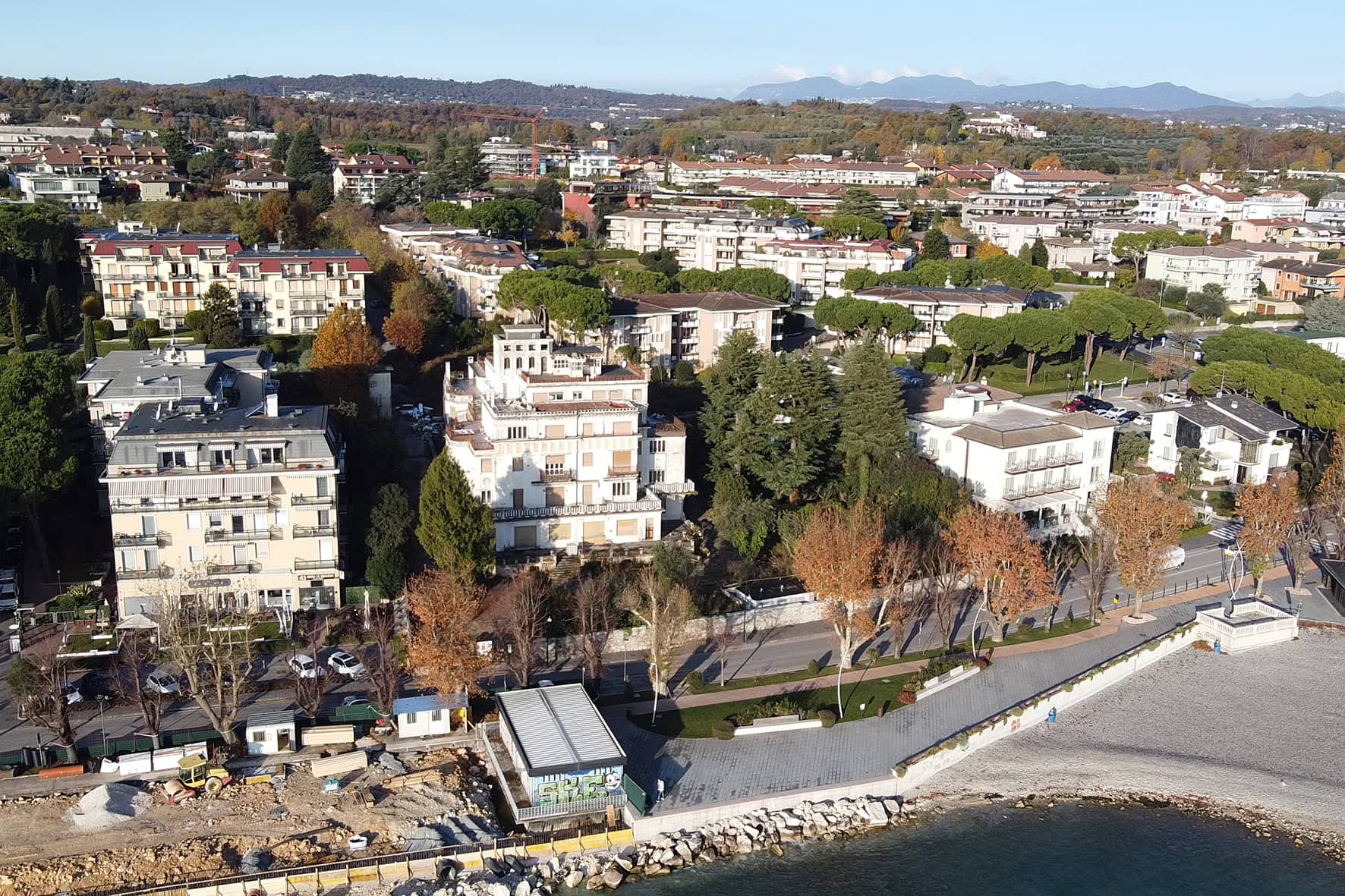 Veduta aerea panoramica del cantiere Villa Olympia Residences a Desenzano del Garda, con il Lago e la città sullo sfondo;
