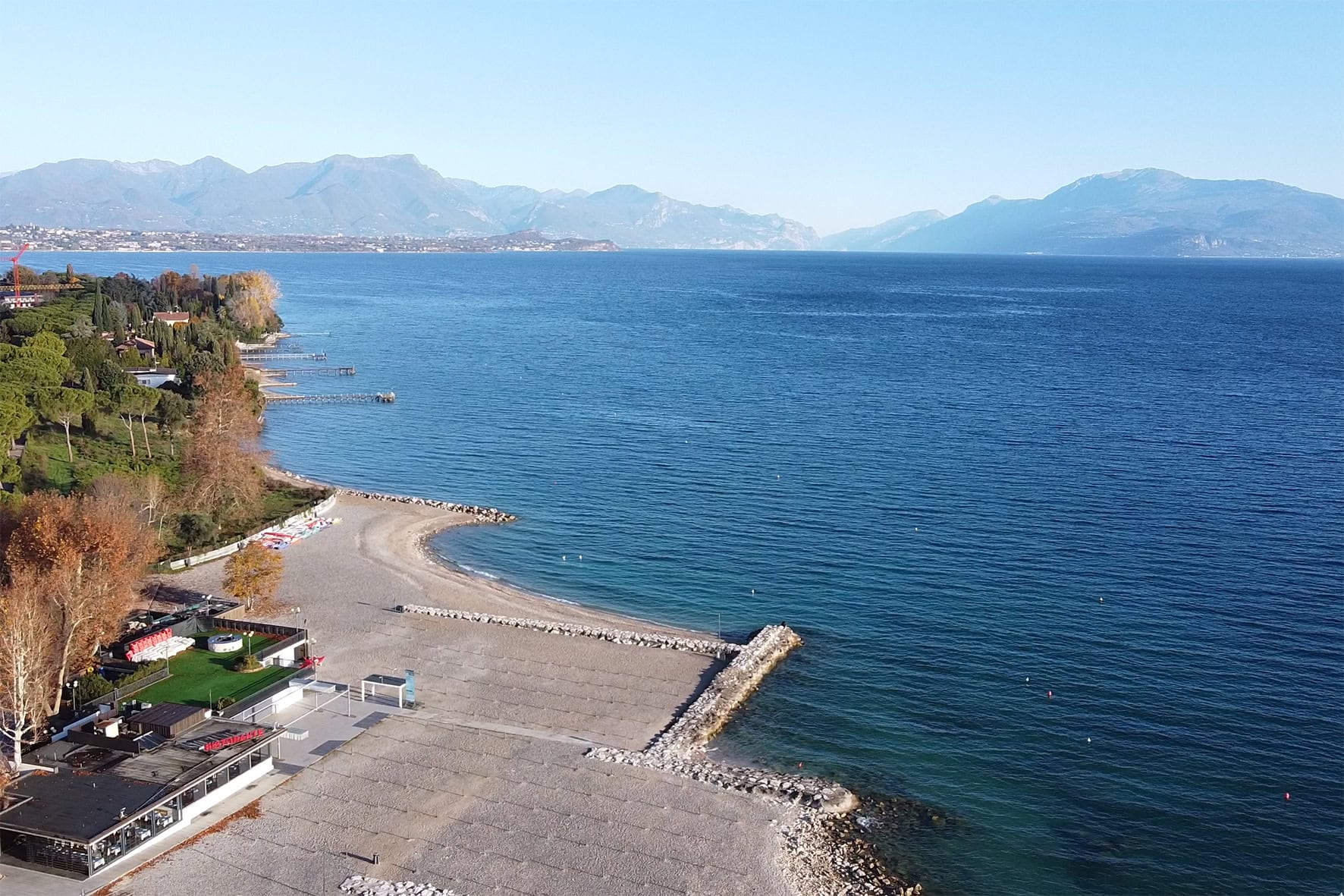 Veduta aerea panoramica del cantiere Villa Olympia Residences a Desenzano del Garda, con il Lago e la città sullo sfondo;