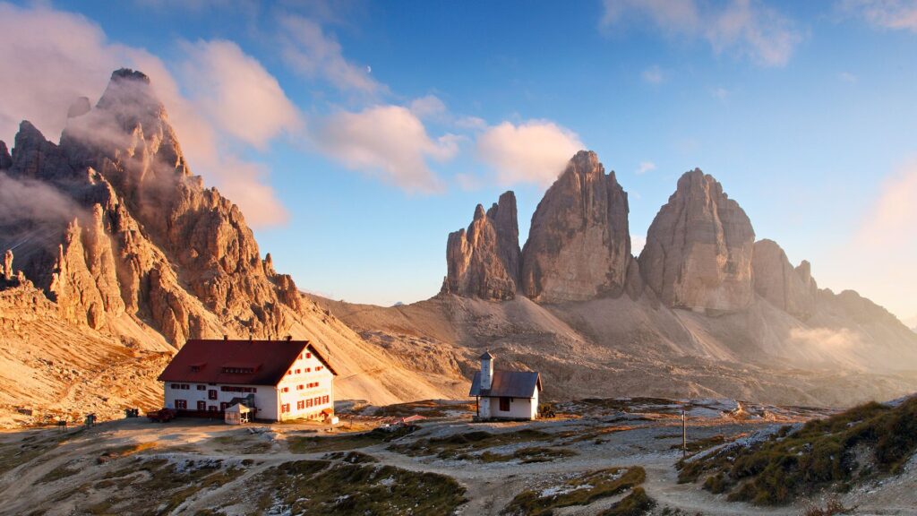 Tre Cime di Lavaredo nelle Dolomiti con rifugio in primo piano al tramonto