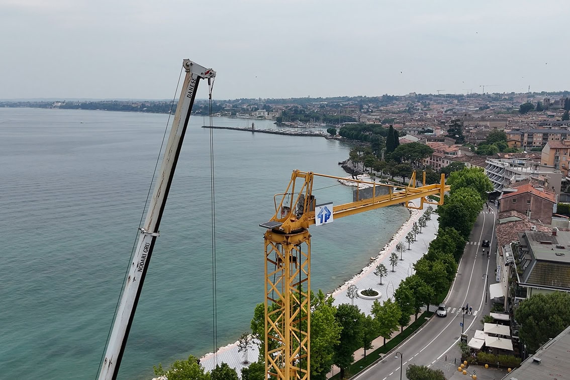Montaggio della gru in corso nel cantiere Villa Olympia Residences: vista ravvicinata sul braccio della macchina e sui blocchi di contrappeso.;